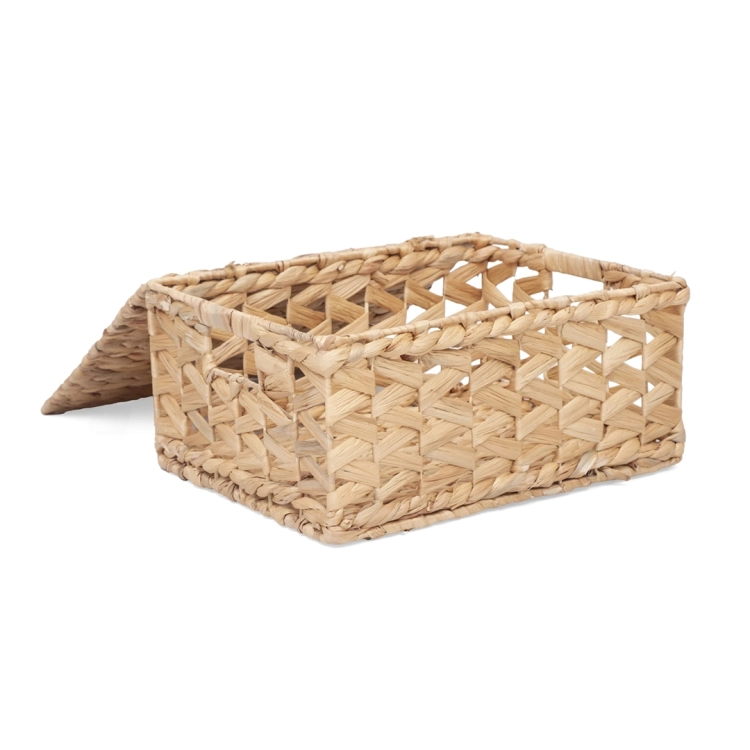 Otwarty kosz pleciony z hiacyntu wodnego z pokrywką opartą o bok.