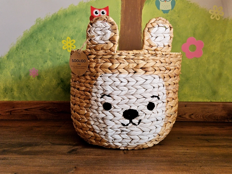 Brązowy kosz na zabawki „Miś” z naturalnych włókien z białym pyszczkiem. Dekoracyjny pojemnik do przechowywania w dziecięcym pokoju, łączący funkcjonalność z estetyką boho.