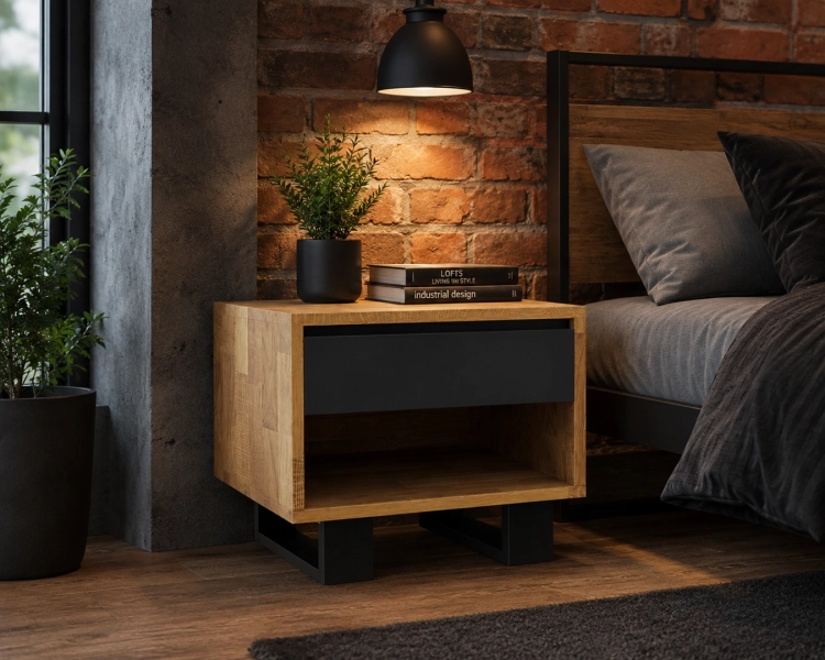 Szafka nocna dębowa drewniana czarna 50 cm z szufladą Vigo w industrialnej sypialni. Mebel z jasnego dębu z czarną wstawką i otwartą półką stoi na metalowych nogach obok łóżka, na tle surowej, ceglanej ściany.