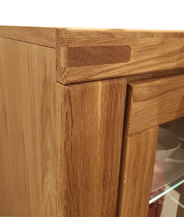 Zbliżenie na szczegóły wykończenia i połączenia drewna w górnej części witryny dębowej Como 2, podkreślające naturalne usłojenie dębu i solidną konstrukcję.